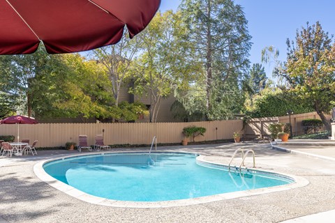A red umbrella shades a swimming pool.