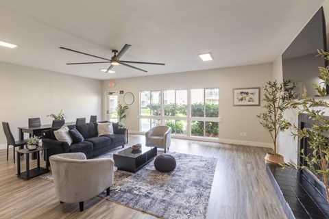 A modern living room with a black sofa, a grey armchair, a coffee table, and a ceiling fan.