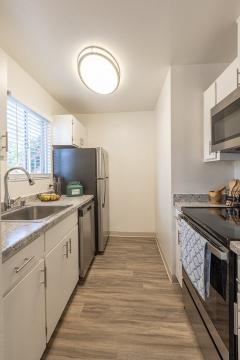 A kitchen with white cabinets and a black fridge.