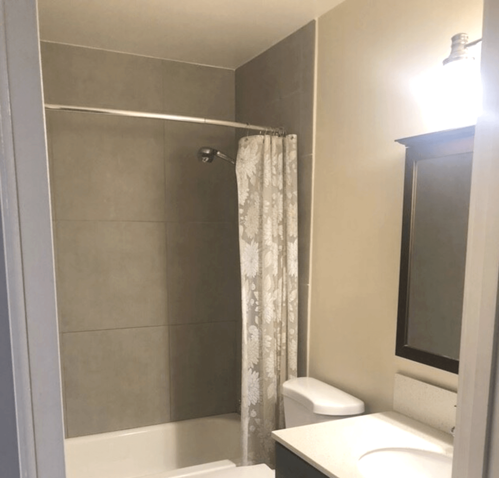 A white toilet sits next to a shower curtain in a bathroom.