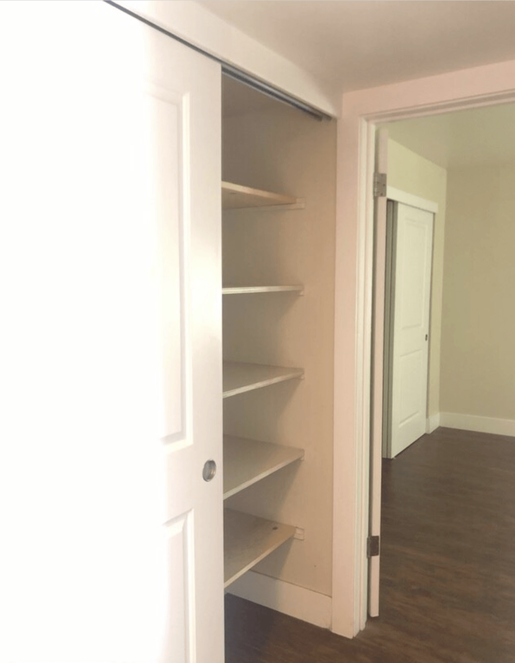 A white door with a shelf underneath it.