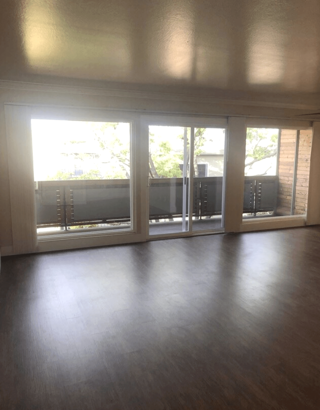 A room with a wooden floor and sliding glass doors.