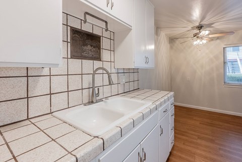 A white kitchen with a sink and a window.