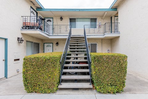 A staircase with a metal railing leads up to a balcony.