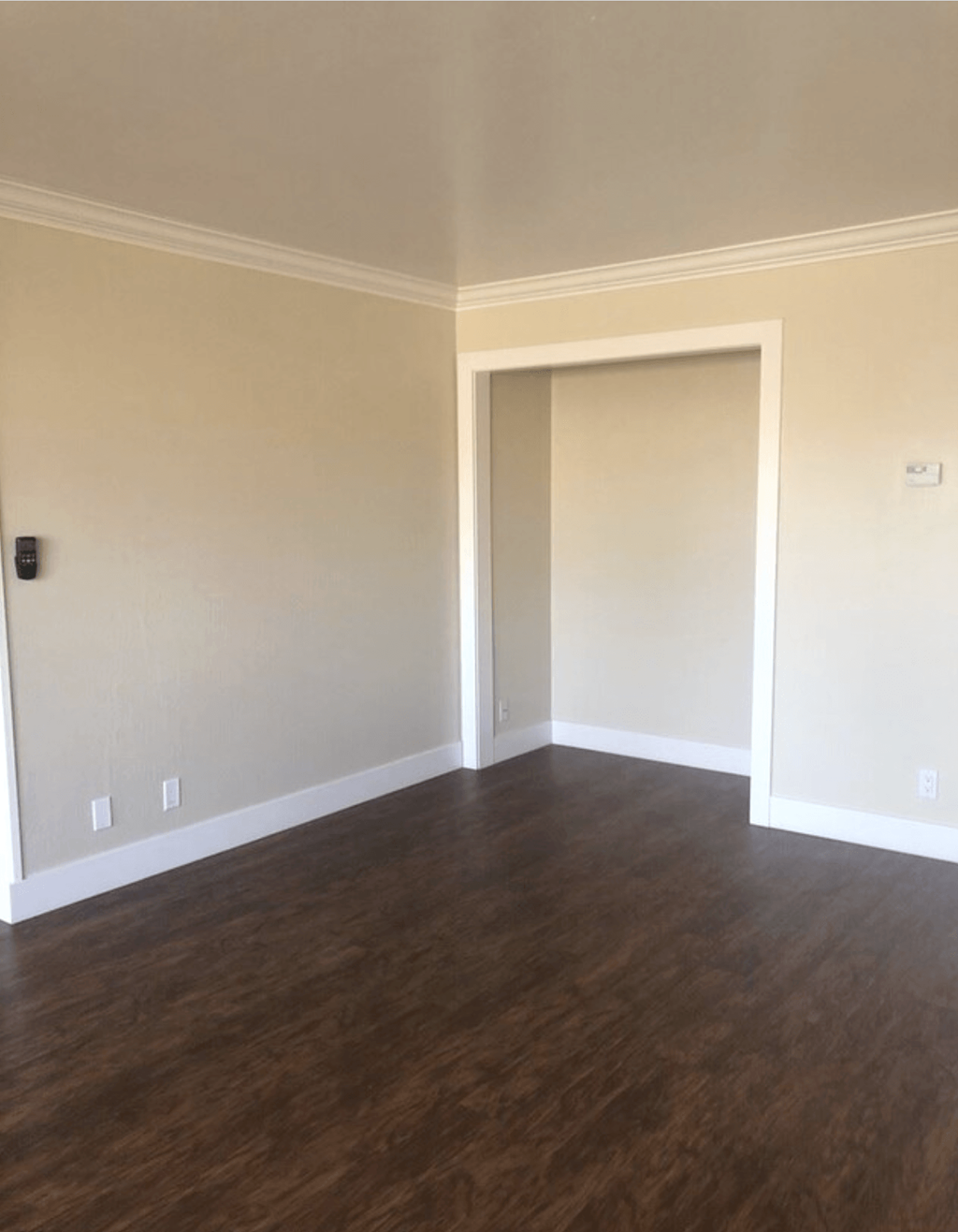 A room with a white door and wooden flooring.