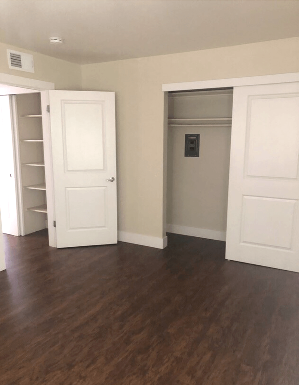 A white door is open to a hallway with wood floors.