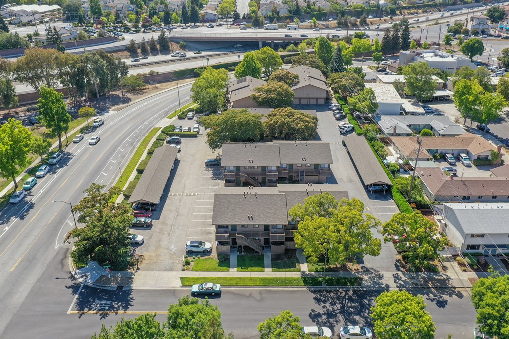 an aerial view of a parking lot with houses and trees