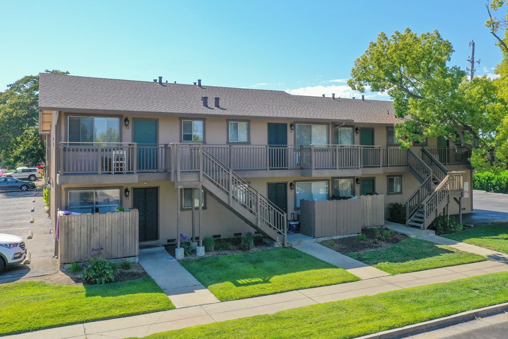 an exterior view of an apartment building with balconies and a lawn
