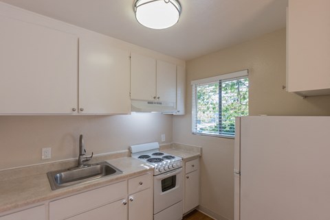 a kitchen with white cabinets and a sink and a refrigerator