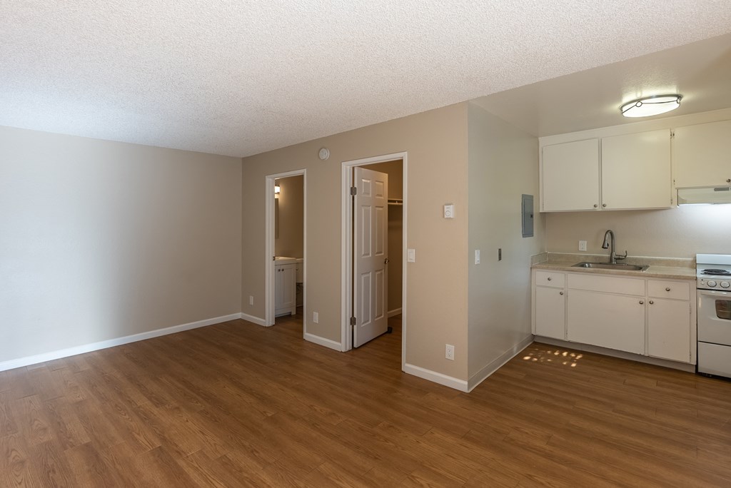 an empty kitchen and living room with a wooden floor
