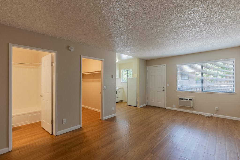 the living room and dining room of an empty house with wood floors and a door