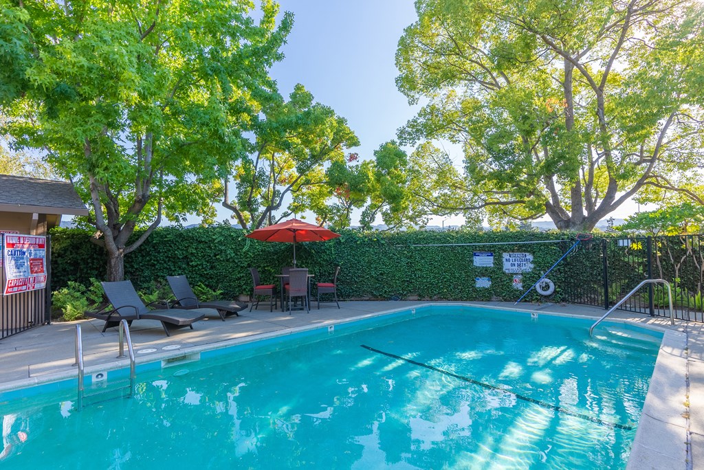 a swimming pool with a poolside table and chairs