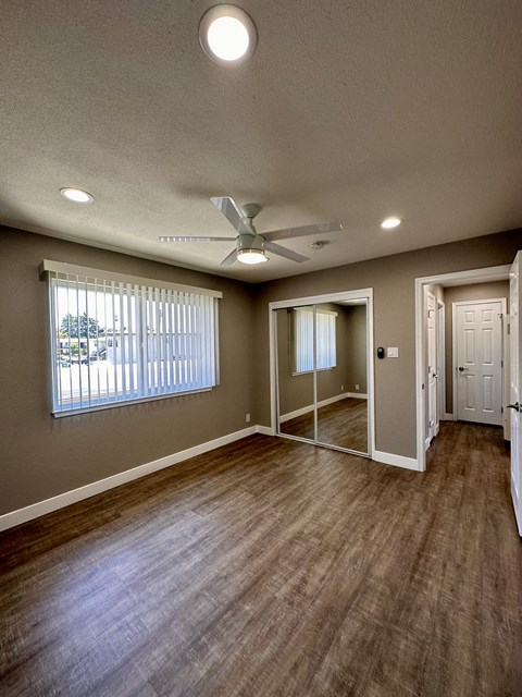 an empty living room with wood floors and a ceiling fan