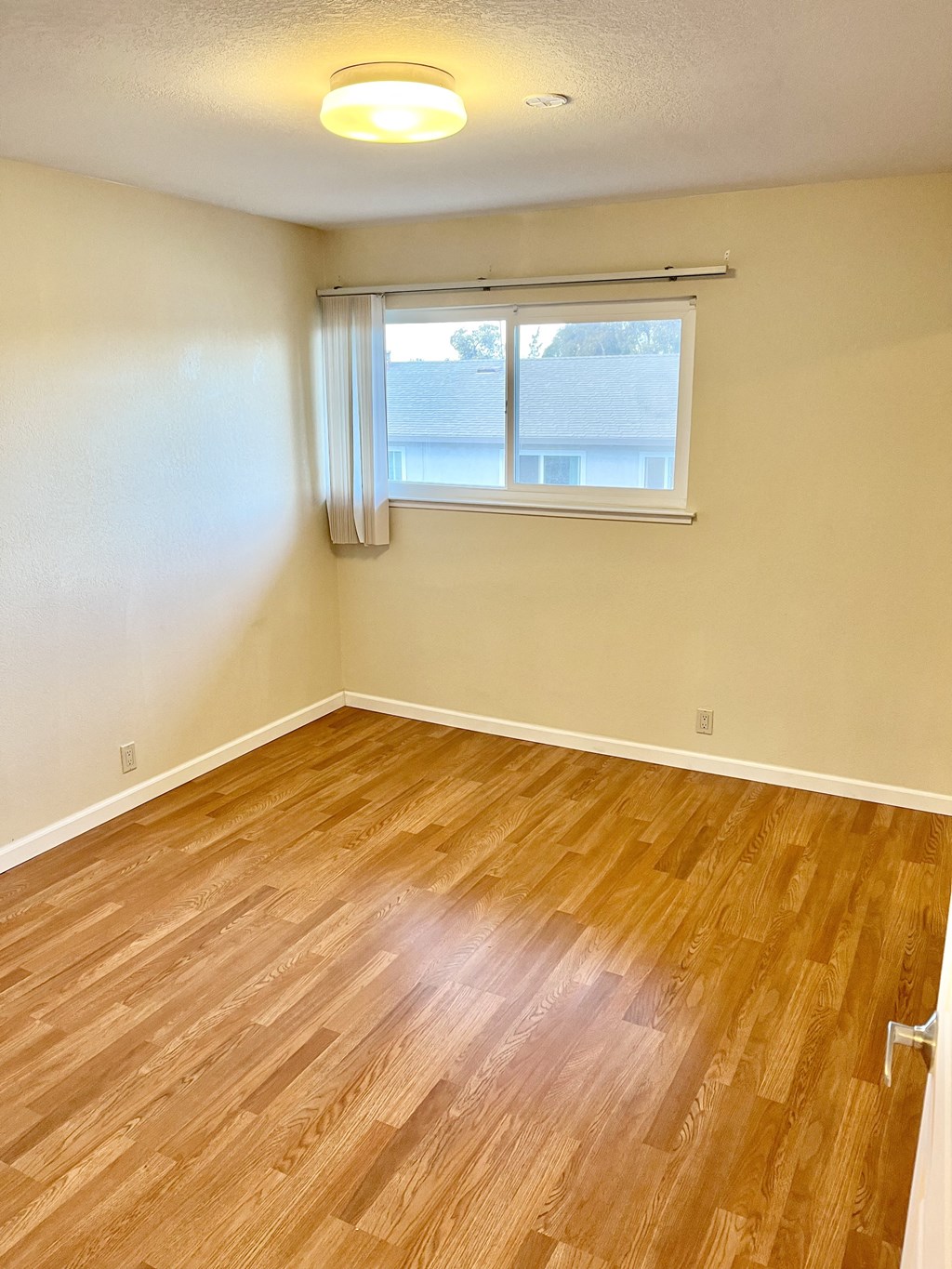 a bedroom with hardwood floors and a window
