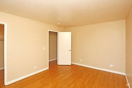 an empty living room with a wooden floor and a white door