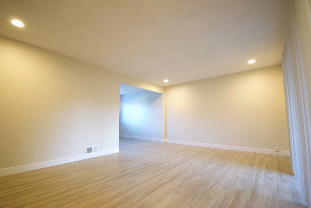 an empty living room with white walls and hardwood floors