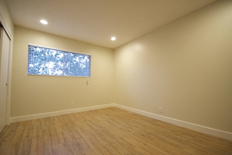 a bedroom with hardwood floors and a large window