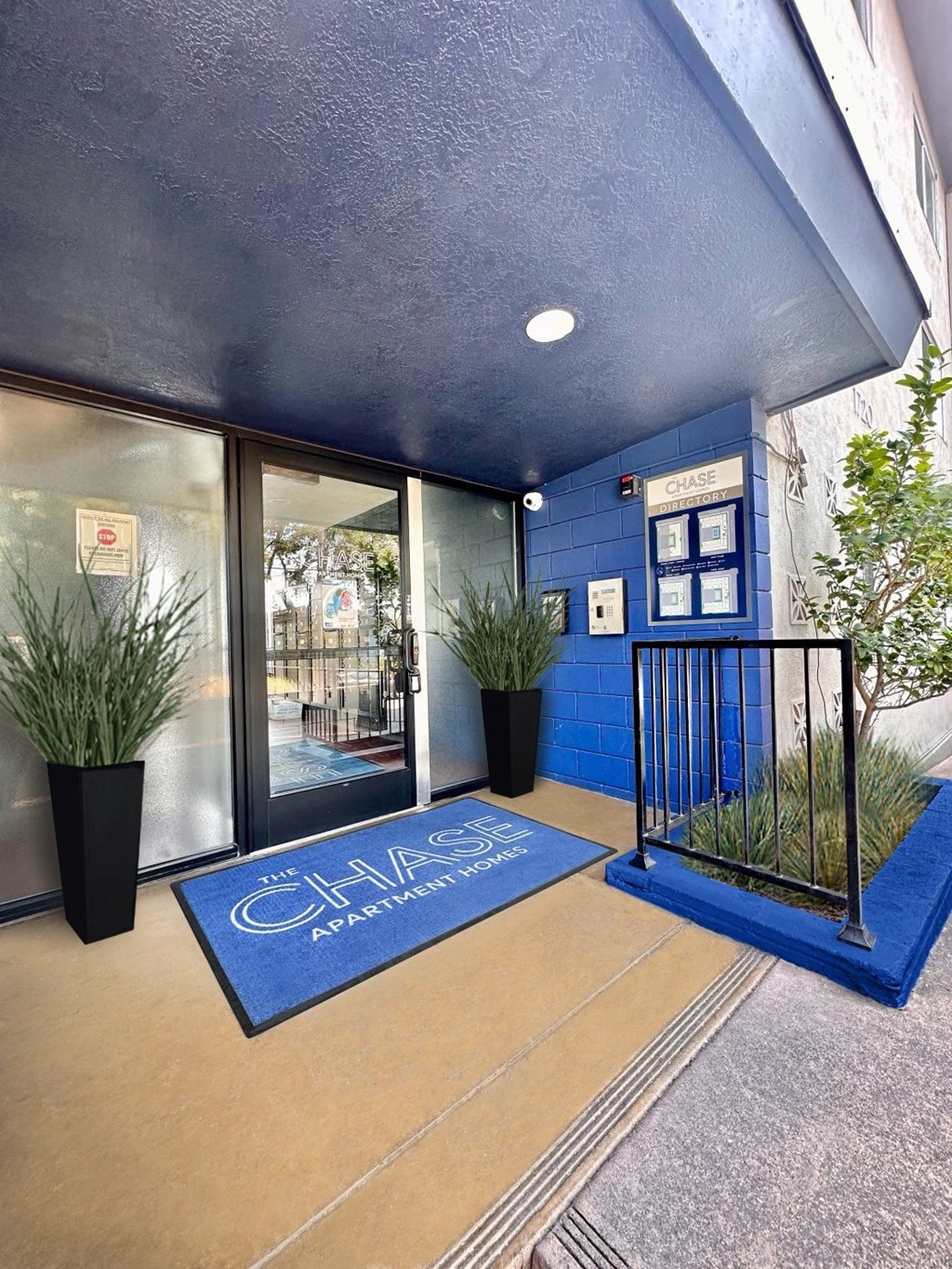 a blue welcome mat in front of a building with a gate