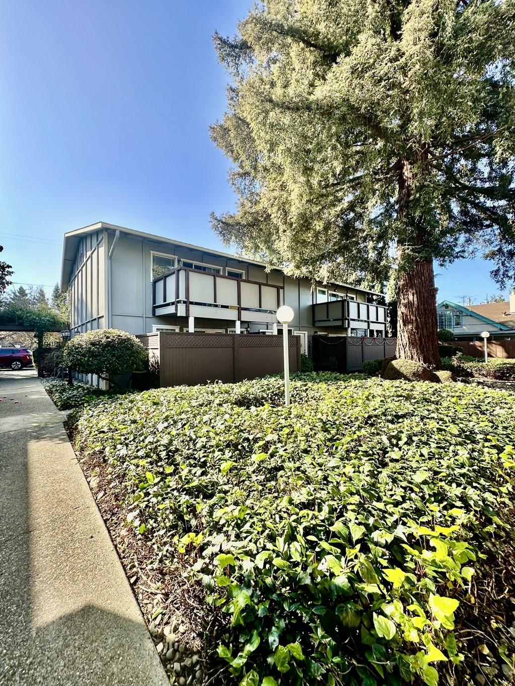 a house with a tree and a sidewalk in front of it