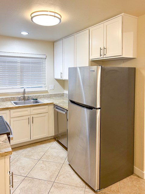 a kitchen with white cabinets and a stainless steel refrigerator