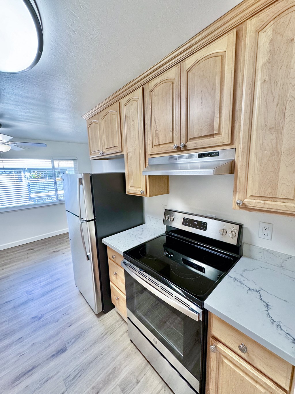 an empty kitchen with wooden cabinets and a stove and refrigerator