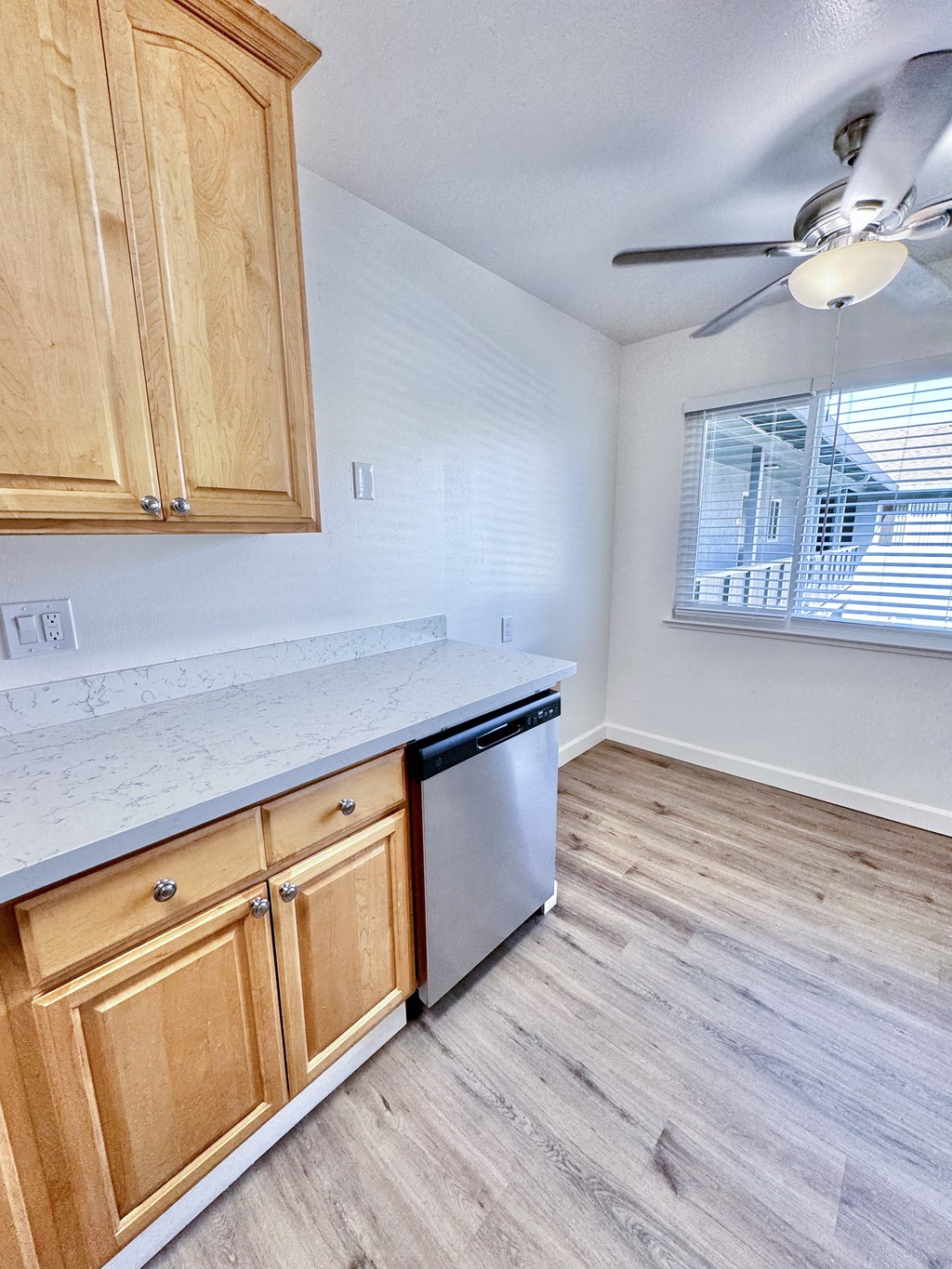 an empty kitchen with a ceiling fan and wooden cabinets