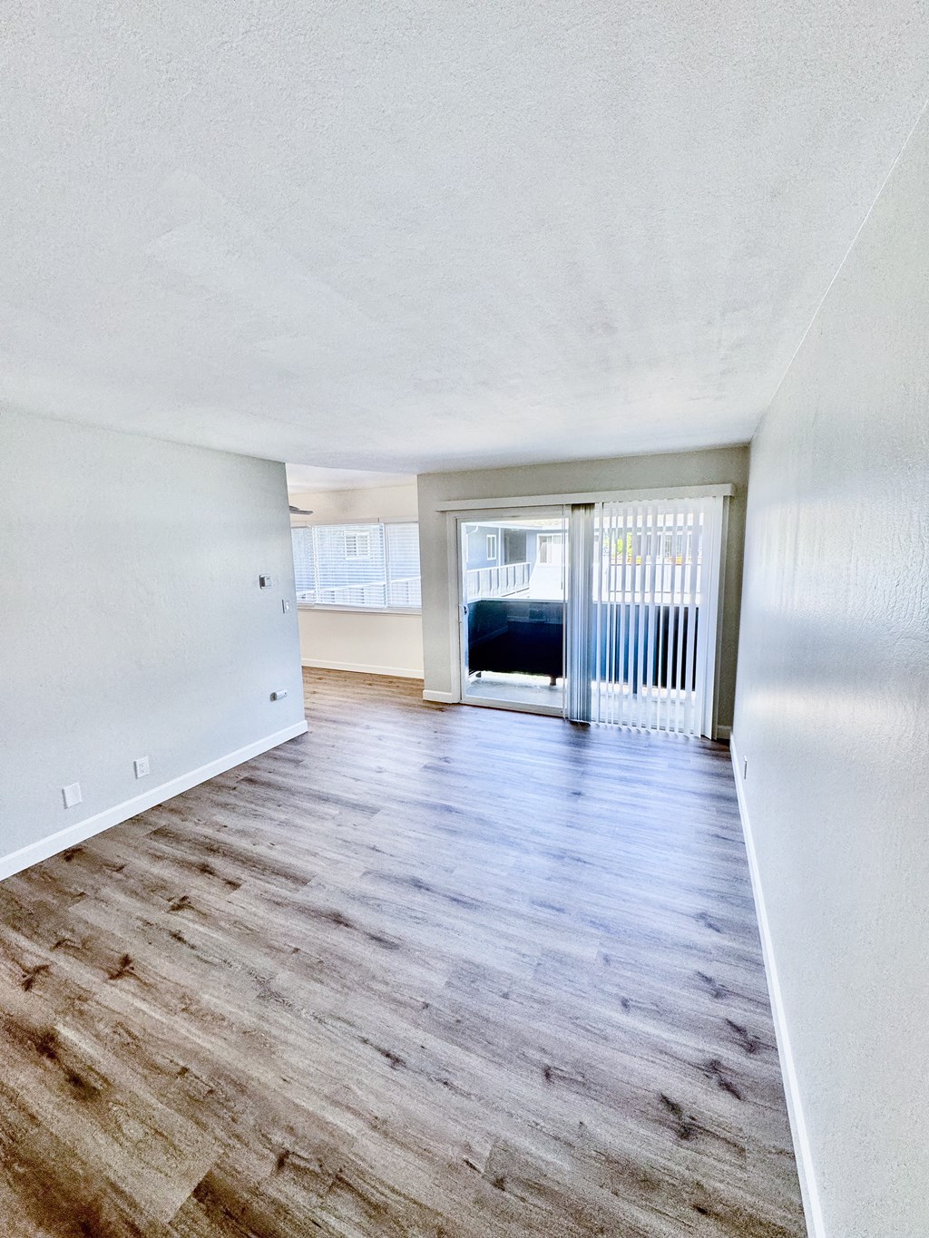 the living room and dining room of an empty home with wood flooring