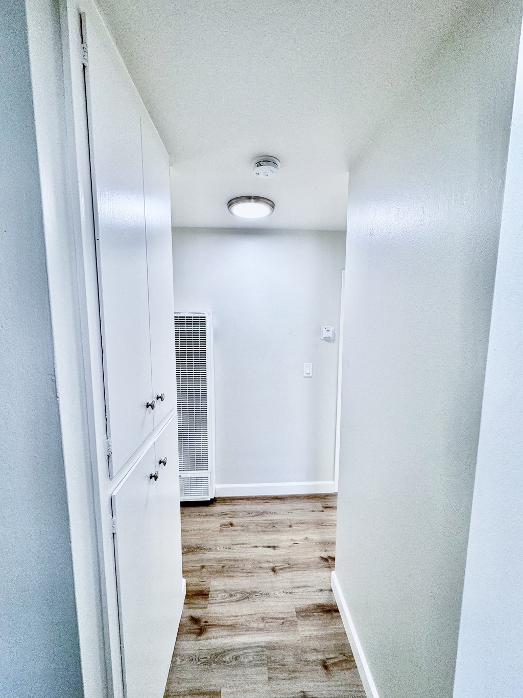 an empty hallway with white walls and a wood floor