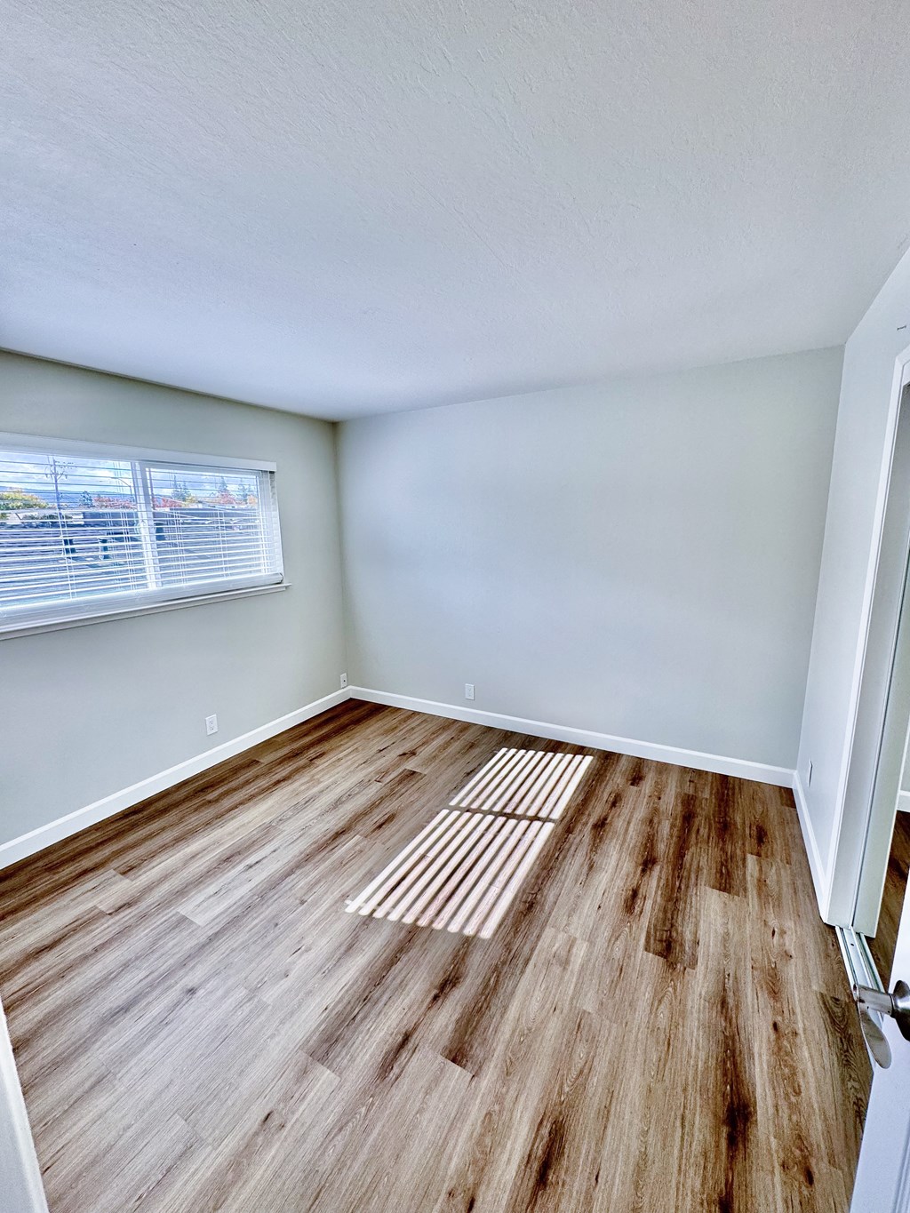 an empty living room with wood floors and a window