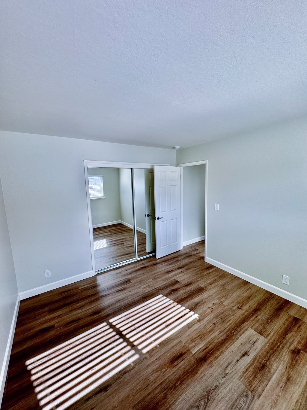 an empty living room with wood floors and a white door