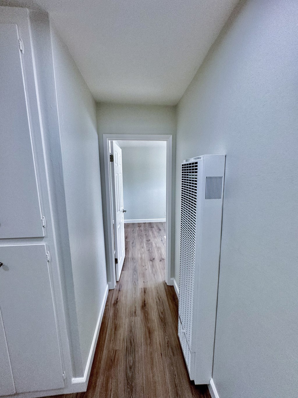 a hallway with a refrigerator and a door to a room