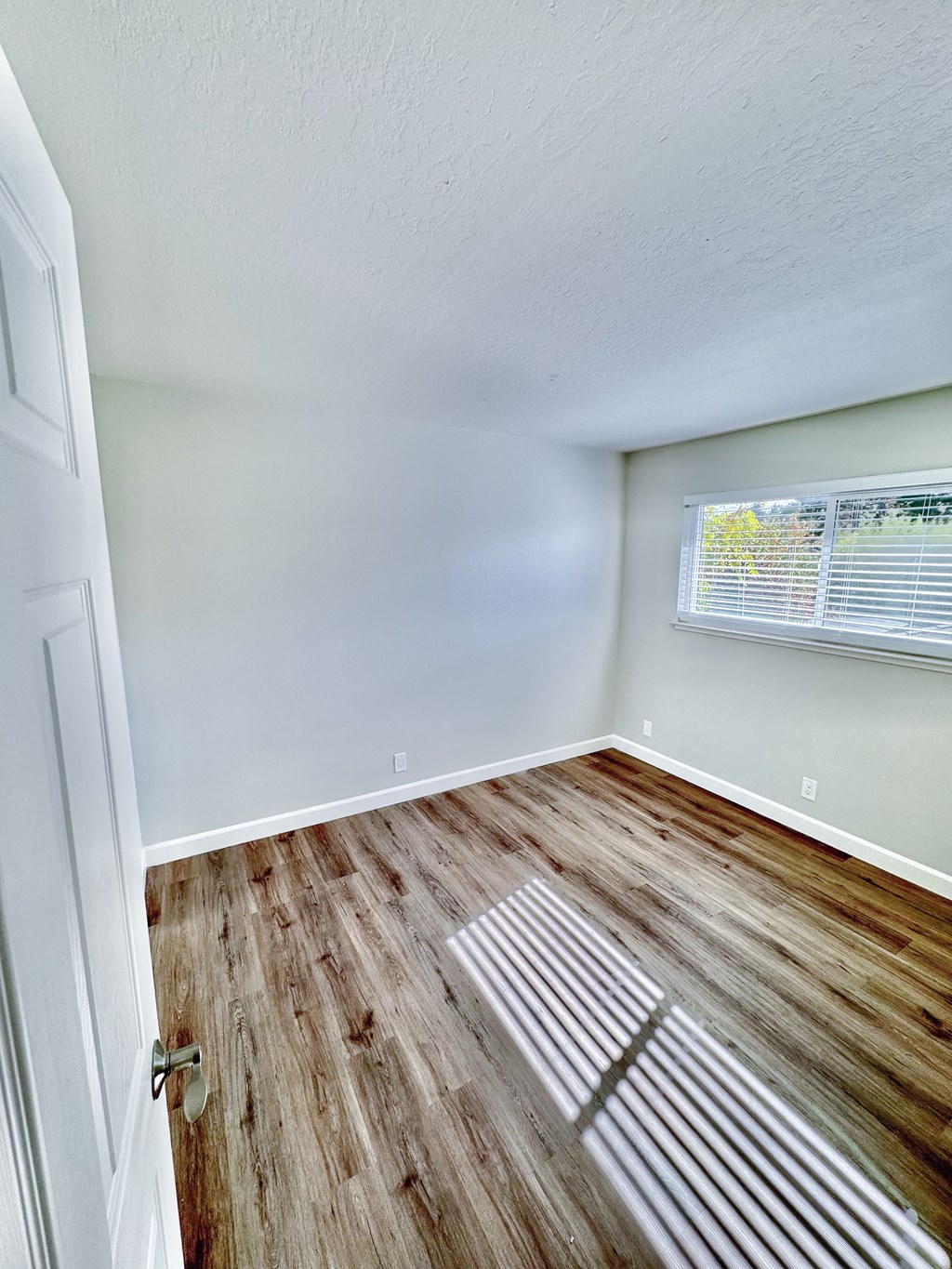 an empty room with wood floors and a window