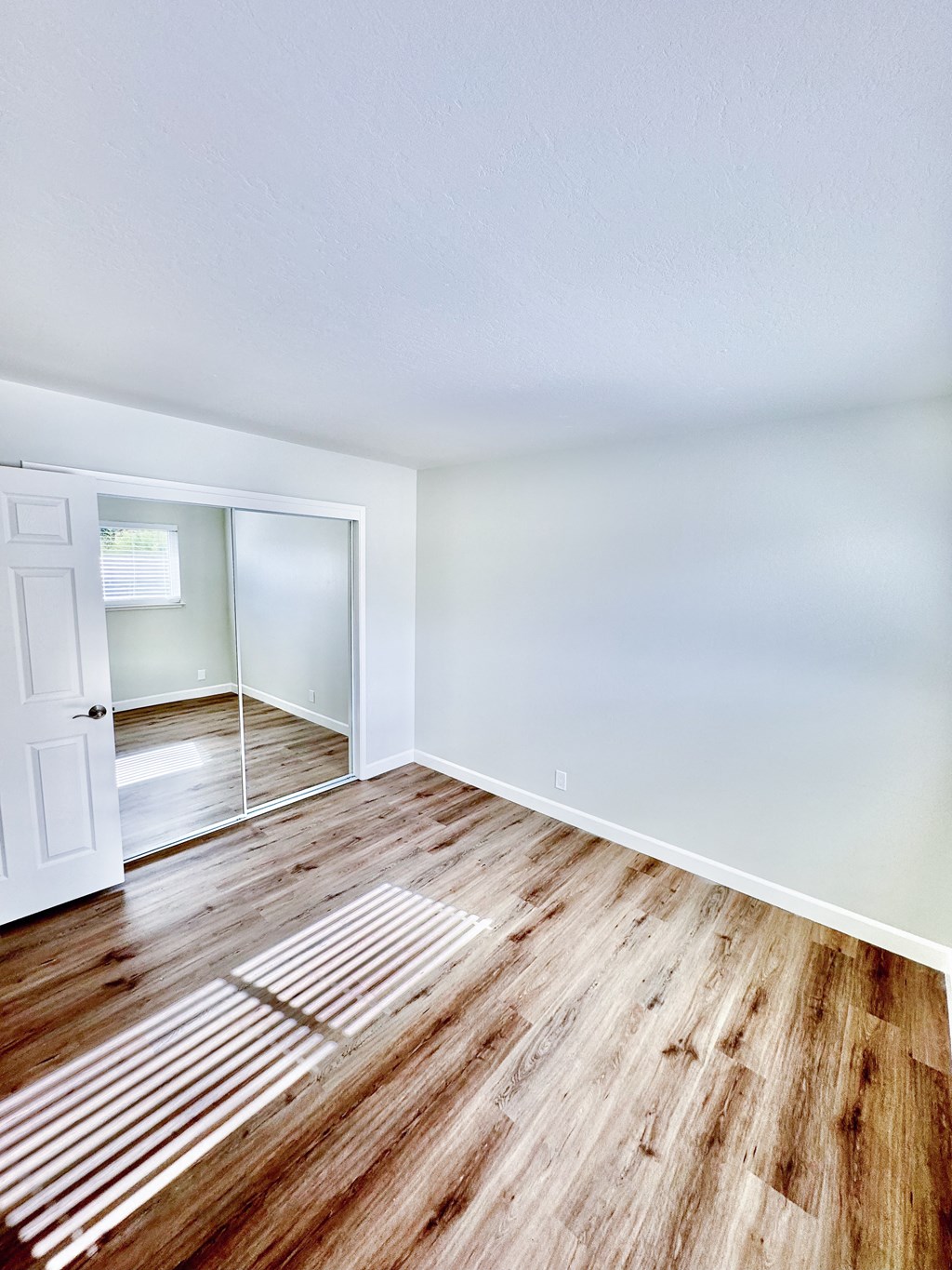 an empty room with hardwood floors and a door to a closet