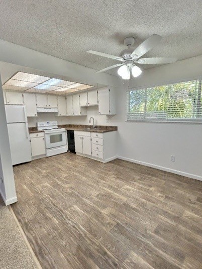 A kitchen with white cabinets and a fan on the ceiling.