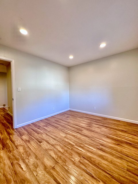 an empty living room with wood flooring and white walls