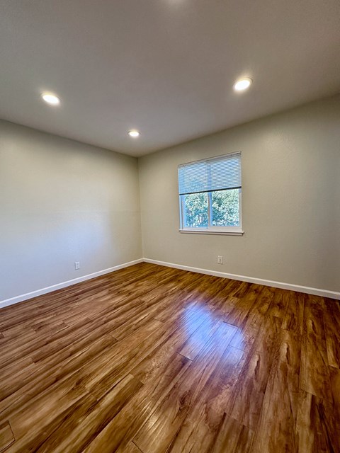 an empty living room with wooden floors and a window
