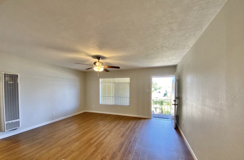an empty living room with a ceiling fan and a window
