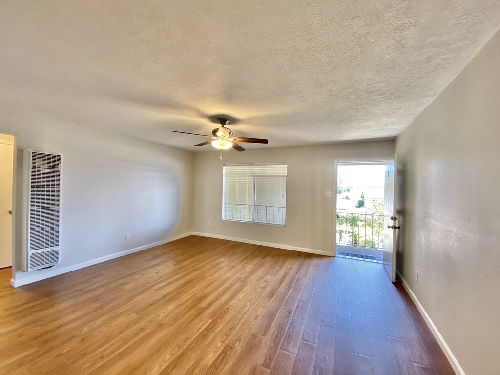 an empty living room with wood floors and a ceiling fan