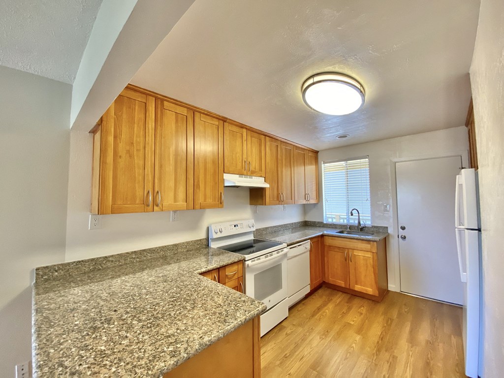 an empty kitchen with granite counter tops and wooden cabinets