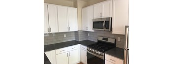 a kitchen with white cabinets and black countertops