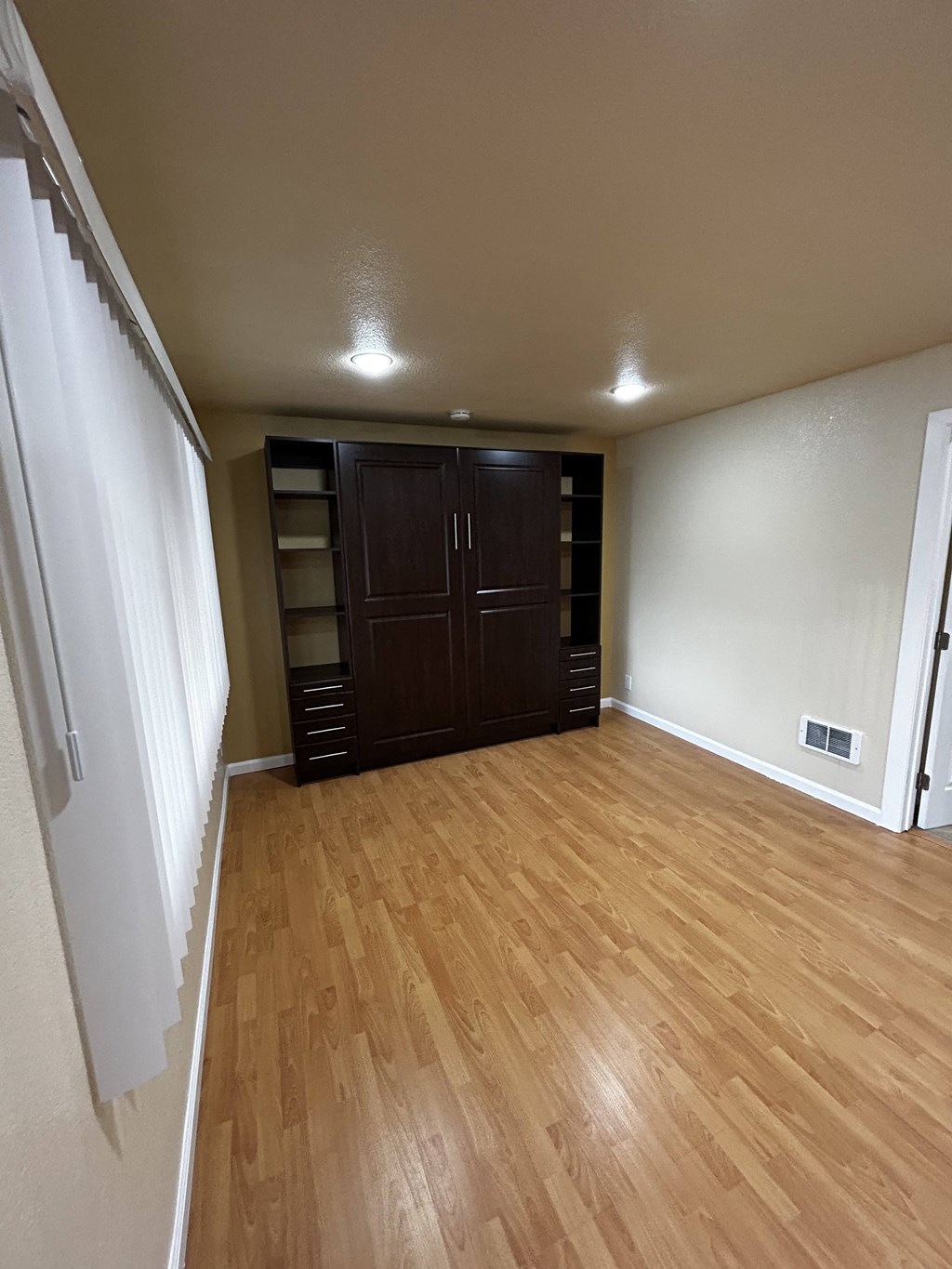 an empty living room with wooden floors and a closet