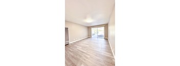 an empty living room with hardwood flooring and a sliding glass door