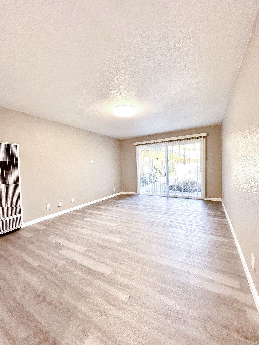 an empty living room with hardwood flooring and a sliding glass door