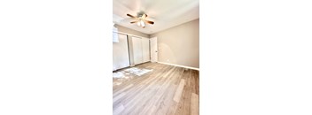 an empty living room with wood flooring and a ceiling fan