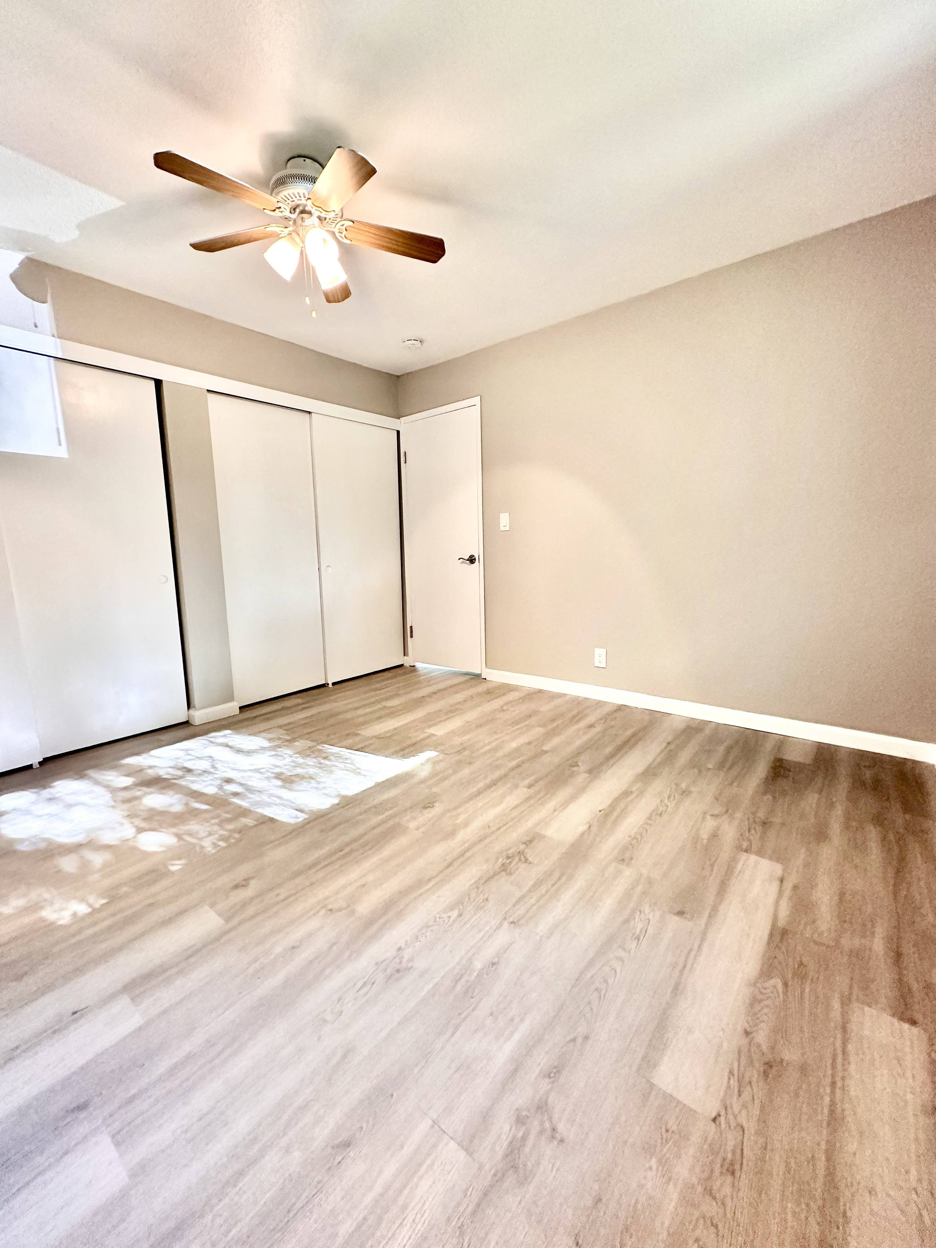 an empty living room with wood flooring and a ceiling fan