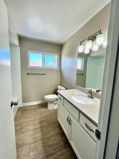 A bathroom with a toilet, sink, and mirror.