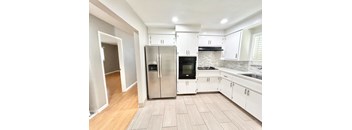 A kitchen with a refrigerator, oven, and sink.