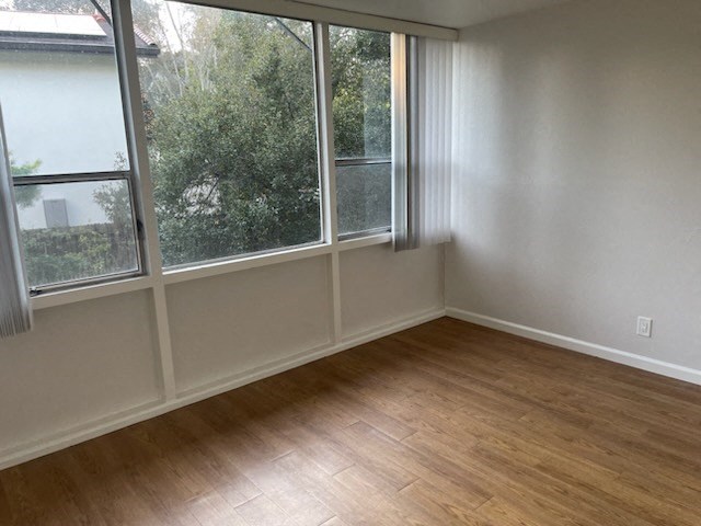 an empty room with a wood floor and large windows