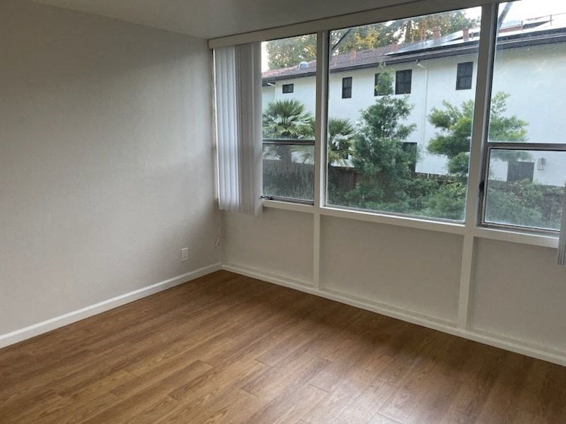 an empty living room with a large window and wooden floors