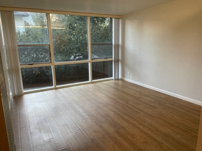 an empty living room with wood floors and a large window